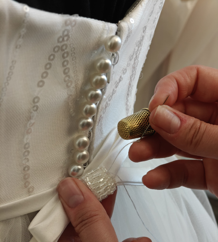 Chiusura con bottoni di perla e cintura ricamata Swarovski su abito da sposa elegante realizzato da Alinda Scudo, sarta su misura ad Alessandria