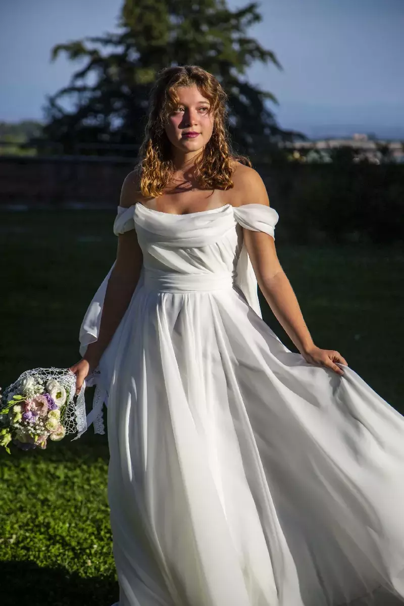Abito da sposa in pizzo con mantella di tulle.